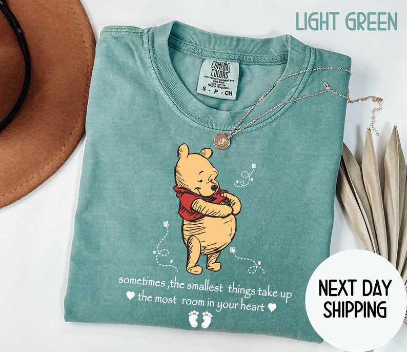 Peut inclure: T-shirt vert clair avec une illustration de Winnie l'ourson en dessin anim&eacute; et le texte "sometimes, the smallest things take up the most room in your heart".