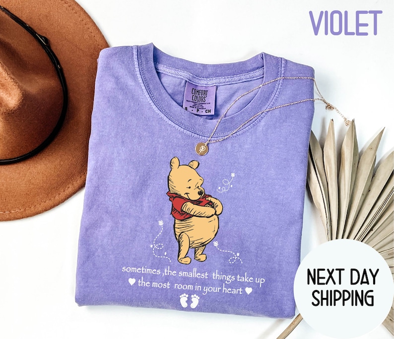 Peut inclure: T-shirt violet avec Winnie l'ourson et la citation "parfois, les plus petites choses prennent le plus de place dans le c&oelig;ur".