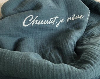 Puede incluir: Una suave manta de muselina azul con el texto "Chuuut, je rêve!" bordado en blanco.