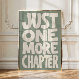 May include: A rectangular wall art print in a gold frame featuring a sage green background with the text JUST ONE MORE CHAPTER in large, bold, off-white sans-serif letters. The print is displayed vertically with a clean, modern aesthetic.