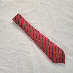 May include: A red silk tie with a repeating pattern of blue and gold chains.