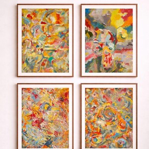 Puede incluir: Cuatro impresiones artísticas abstractas enmarcadas. Cada impresión presenta una vibrante mezcla de colores que incluye amarillo, naranja, rojo, azul y verde. La obra de arte se muestra en marcos de madera marrón sobre una pared blanca.