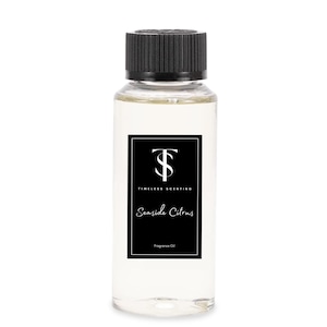 May include: A clear glass bottle with a black cap and label. The label has a black and white logo with the text "Timeless Scenting" and the words "Seashore Citrus" in a white script font. The label also says "Fragrance Oil".
