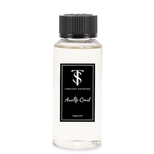 May include: A clear glass bottle with a black cap and label. The label has a black and white logo with the text "Timeless Scenting" and the words "Amalfi Coast" in a white script font. The label also says "Fragrance Oil".