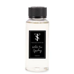 May include: A clear glass bottle with a black cap and a black and white label. The label says "Timeless Scenting" and "White Tea Symphony" in white text. The bottle contains fragrance oil.