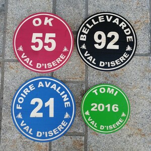 Puede incluir: Cuatro letreros redondos y coloridos con texto blanco y un gráfico de abeja. Los letreros dicen "Ok 55 Val d'Isere", "Bellevarde 92 Val d'Isere", "Foire Avaline 21 Val d'Isere" y "Tomi 2016 Val d'Isere".