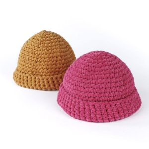 Peut inclure: Deux chapeaux crochetés à la main. L'un est de couleur jaune moutarde, l'autre est magenta vif. Les deux chapeaux ont une couronne arrondie et un bord replié. Les chapeaux sont faits d'un fil doux et texturé.