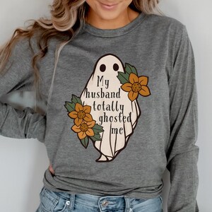 May include: A gray long-sleeved shirt with a white ghost graphic and the text "My husband totally ghosted me". The ghost has orange flowers around it.