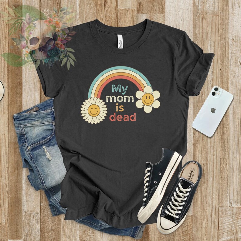 May include: Black t-shirt with a rainbow and two yellow flowers with smiley faces. The text "My mom is dead" is printed on the shirt.