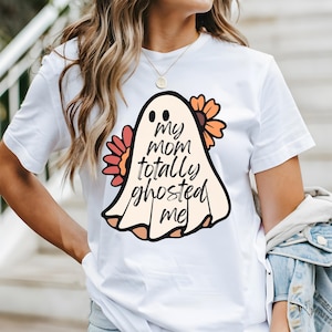 May include: White t-shirt with a ghost graphic and the text "My mom totally ghosted me". The ghost is surrounded by orange and red flowers.