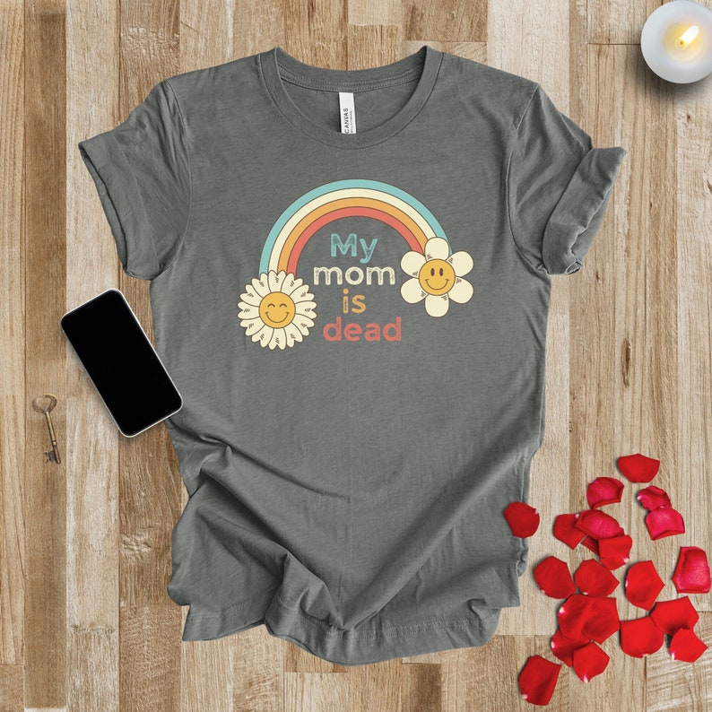 May include: A gray t-shirt with a rainbow and two yellow flowers with smiley faces. The text on the shirt reads "My mom is dead."