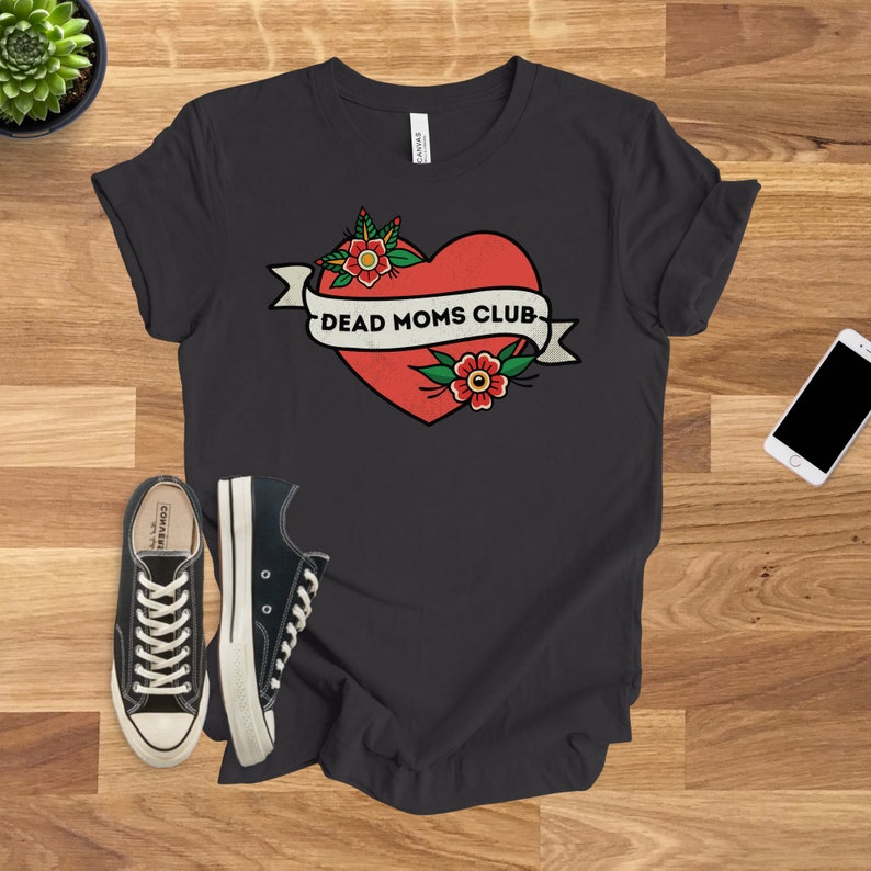 May include: A black t-shirt with a red heart and a banner that says "Dead Moms Club". The heart has two red flowers with yellow centers.
