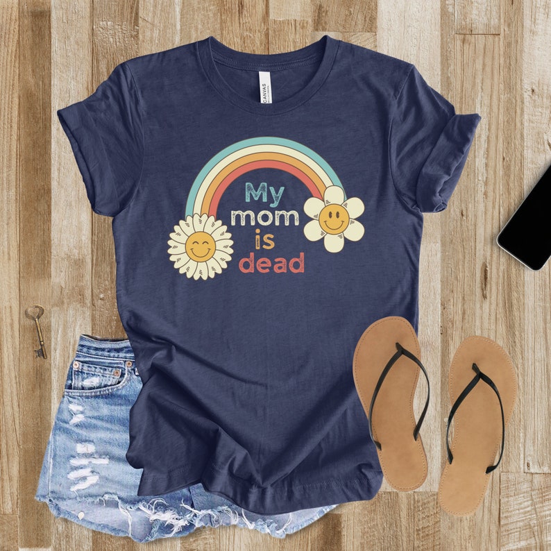 May include: A navy blue t-shirt with a rainbow, two yellow flowers with smiley faces, and the text "My mom is dead".