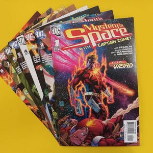 May include: A collection of DC comic books, with the title "Mystery in Space with Captain Comet." The comic covers are brightly coloured, depicting superheroes and space-themed scenes. The background is a solid yellow.