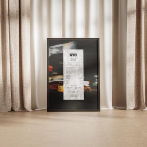 May include: A framed print depicting a blurred night street scene with a central receipt. The receipt, labelled "NYC", is detailed with itemised listings. The frame is dark, and the background shows yellow taxi cabs.