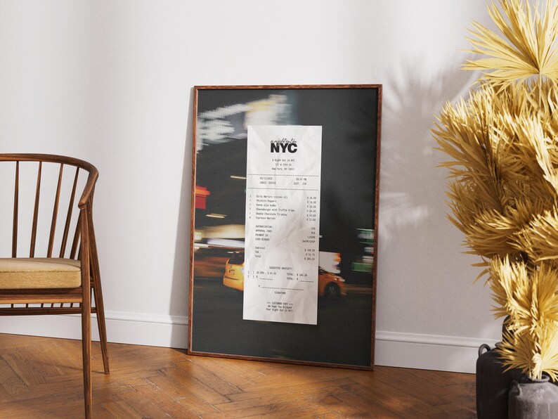 May include: Framed print depicting a blurred night street scene with yellow taxi cabs and a large receipt. The receipt has the text "NYC" at the top. The frame is a dark brown colour.