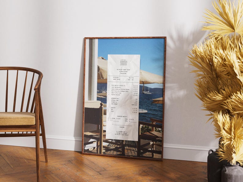 Peut inclure: Une photographie encadr&eacute;e d'un re&ccedil;u d'un restaurant appel&eacute; "The Pretty Sunset Tavern" avec une vue sur une &eacute;tendue d'eau bleue avec des bateaux et un parasol blanc au premier plan.