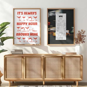 May include: Two framed prints hang above a wooden cabinet. One features the text "IT'S ALWAYS HAPPY HOUR AROUND HERE" in red, with cocktail glass illustrations. The other is a black and white photograph of a receipt.