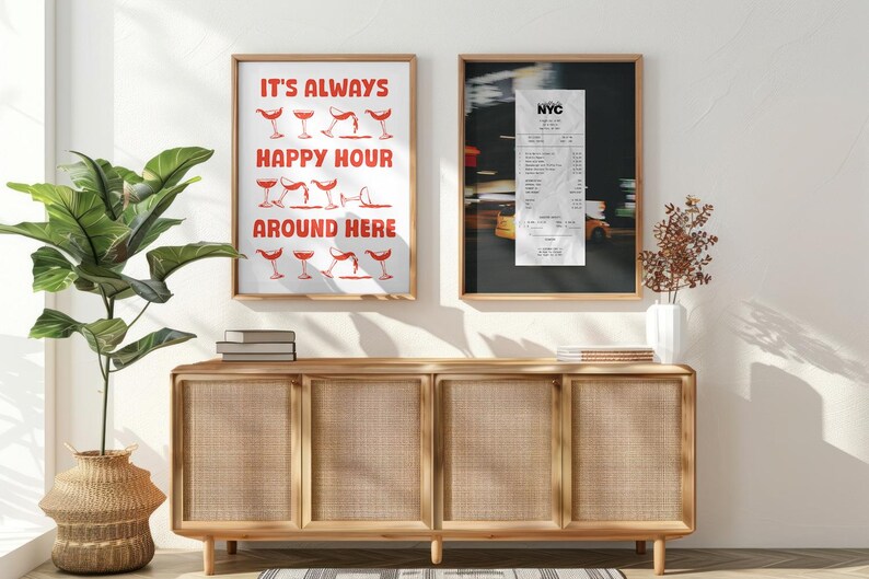 May include: Two framed prints hang above a wooden cabinet. One features the text "IT'S ALWAYS HAPPY HOUR AROUND HERE" in red, with cocktail glass illustrations. The other is a black and white photograph of a receipt.