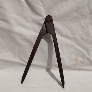 May include: A rusty metal compass with a pointed tip on each end. The compass is open and ready to be used for drawing circles or measuring distances.