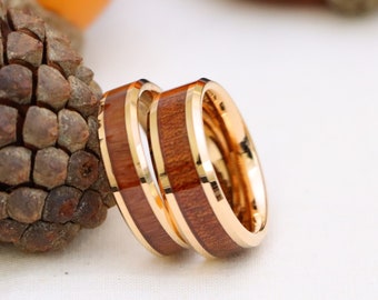 May include: Two gold wedding bands with a brown wood inlay. The bands are stacked on top of each other.