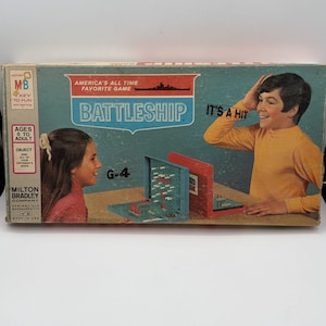 May include: A vintage Milton Bradley Battleship board game box featuring a blue and red color scheme. The box displays the text America's All Time Favorite Game, Battleship, It's A Hit, and G-4. It shows illustrations of two people playing.
