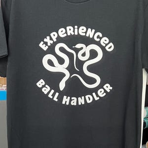 May include: Black t-shirt with a white graphic of two snakes intertwined and the text "Experienced Ball Handler".
