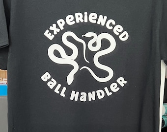 Puede incluir: Camiseta negra con un gráfico blanco de dos serpientes entrelazadas y el texto "Experienced Ball Handler".