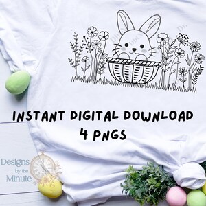 May include: White t-shirt with a black and white drawing of a rabbit in a basket amidst flowers and grass. The text "INSTANT DIGITAL DOWNLOAD 4 PNGS" is printed below. The shirt has a round neckline. The design is suitable for digital download.
