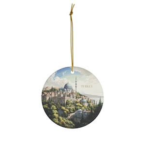 May include: A round ceramic bauble featuring a depiction of a mosque in Istanbul, Turkey. The bauble has a gold string for hanging.