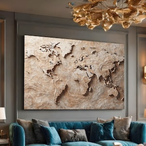 May include: A large, textured world map art piece in shades of beige and brown. The map is mounted on a wall above a blue sofa. The artwork features raised relief details of continents and oceans, creating a three-dimensional effect.