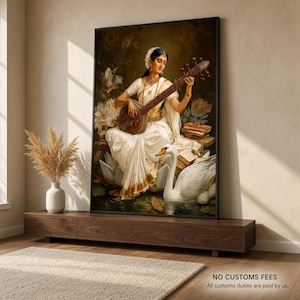 May include: A framed wall art print depicting a person in a white and gold sari playing a veena while seated on a large lotus flower. A white swan is positioned in the water below, surrounded by white lotus blossoms and stacked books.
