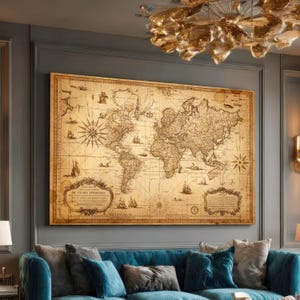 Op de afbeelding: Een grote, vintage wereldkaartprint met een sepia-tint, ingelijst en aan een grijze muur bevestigd. De kaart toont gedetailleerde cartografie, windrozen en illustraties van schepen. Een blauwe bank staat onder het kunstwerk.