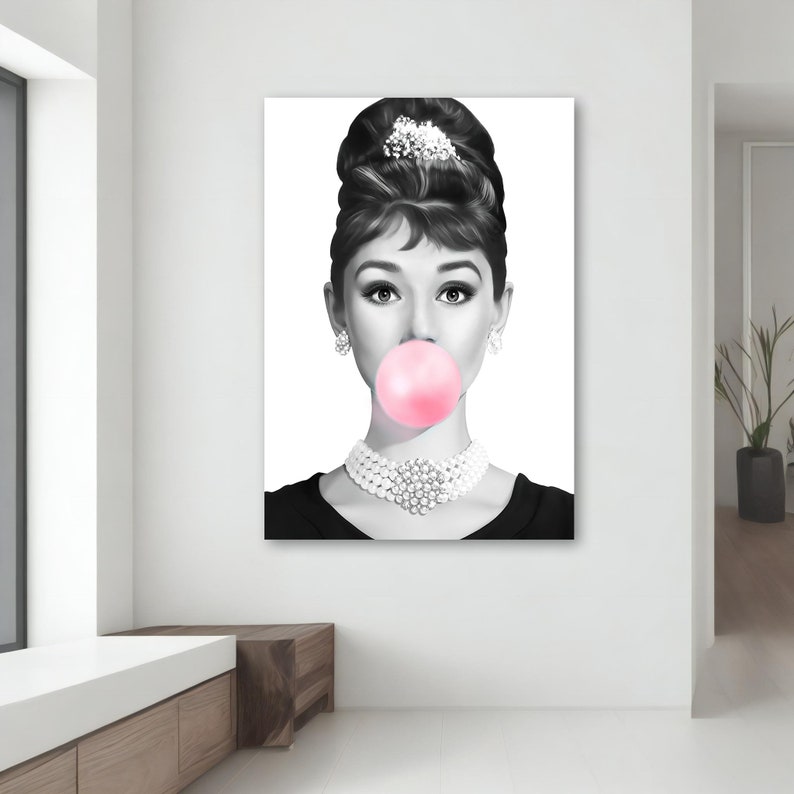 May include: Black and white portrait of a woman with a bouffant hairstyle wearing a pearl necklace and blowing a pink bubble.