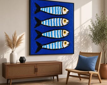 May include: A rectangular wall art piece featuring four stylized fish arranged horizontally in a stack. Each fish has a white body with vertical blue stripes, a black tail, and a yellow eye, all set against a solid, deep blue background.
