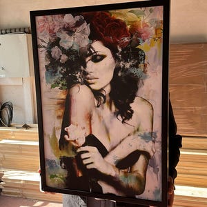 Pu&ograve; includere: Stampa artistica incorniciata raffigurante una donna con elementi floreali tra i capelli. L'opera d'arte ha uno stile morbido e pittorico con una tavolozza di rosa, blu e rossi. La cornice nera aggiunge un tocco moderno.