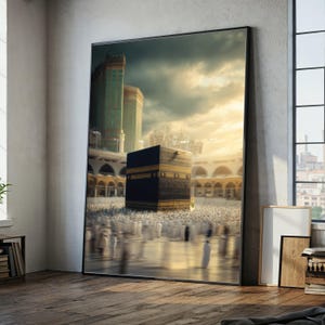 Pode incluir: Impressão emoldurada da Kaaba em Meca, Arábia Saudita. A estrutura preta em forma de cubo é cercada por pessoas vestidas de branco. A imagem tem uma luz quente e dourada e retrata uma cena religiosa.
