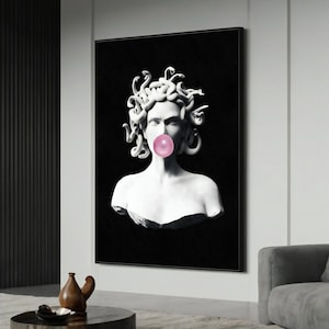 Peut inclure: Un portrait en noir et blanc d'une femme avec des serpents pour cheveux soufflant une bulle rose. L'arrière-plan est noir.