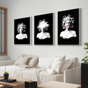 May include: Three framed art prints featuring white busts of Medusa on a black background. One has a cloud in place of a face, another has a bubblegum bubble, and the third has a face. The art is displayed above a white sofa.