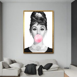 May include: Black and white portrait of a woman with a large pink bubble gum in her mouth. She is wearing a pearl necklace and a black dress.
