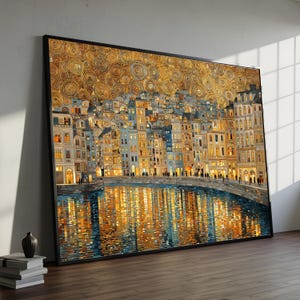 Può includere: Stampa artistica incorniciata raffigurante un paesaggio urbano notturno. Gli edifici sono in tonalità di blu, oro e beige, con illuminazione interna calda. L'acqua riflette le luci della città. Il cielo è un motivo dorato di cerchi concentrici.