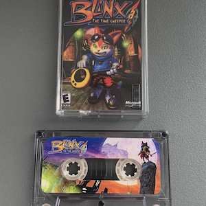 May include: An Xbox game case and a cassette tape featuring the game "Blinx: The Time Sweeper." The game case has a colorful illustration of a cat-like character. The cassette tape has a matching design.