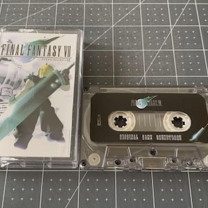 Puede incluir: Un casete de Final Fantasy VII con una funda de plástico transparente. La portada presenta un personaje con una espada grande. El casete es negro con texto blanco que dice "ORIGINAL GAME SOUNDTRACK".