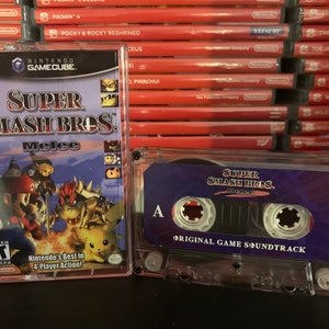 May include: A Nintendo GameCube game case and a cassette tape of the Super Smash Bros. Melee soundtrack. The game case features a colorful cover with characters like Mario and Pikachu. The cassette tape has a purple label.