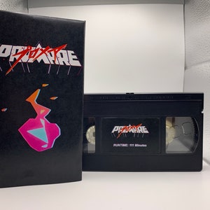 May include: A black VHS tape and case with the word "PROXAIRE" in white and red stylized text. The case features a geometric design in pink, orange, and blue. The tape reads "RUNTIME: 111 Minutes".