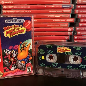 May include: A Sega Genesis game cartridge and cassette tape for "ToeJam & Earl in Panic on Funkotron." The game case has a red border with the Sega Genesis logo. The cassette tape has a blue label with the game title.