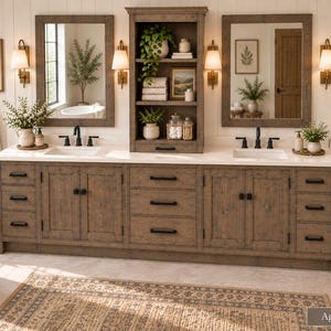 May include: A double bathroom vanity in an aged barrel wood finish with a white countertop, two rectangular sinks, and black hardware. It features two mirrors, wall-mounted lights, and a central shelving unit containing towels and decor items.