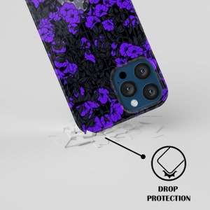 May include: A black phone case with a purple floral pattern. The case has a raised camera bump with three lenses. The case is shown on a broken white surface with a drop protection icon.
