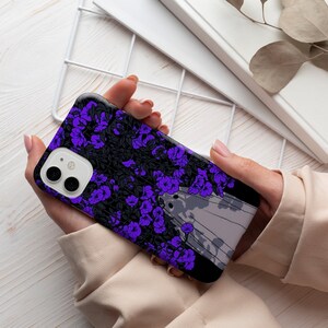 May include: A black phone case with a purple floral design and a white and gray abstract design. The case has a camera lens cutout.