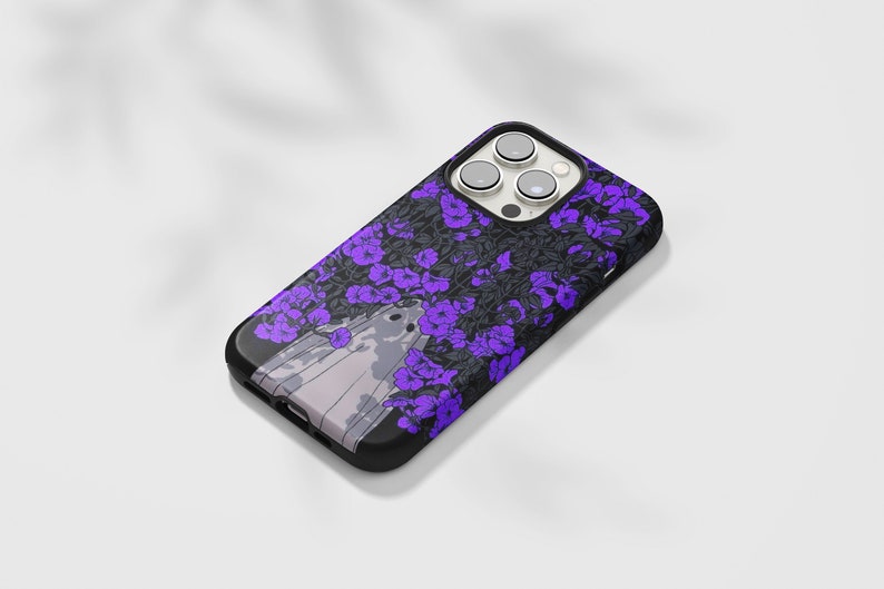 May include: A black phone case with a purple floral design and a ghost in the center. The phone case has a camera lens cutout.